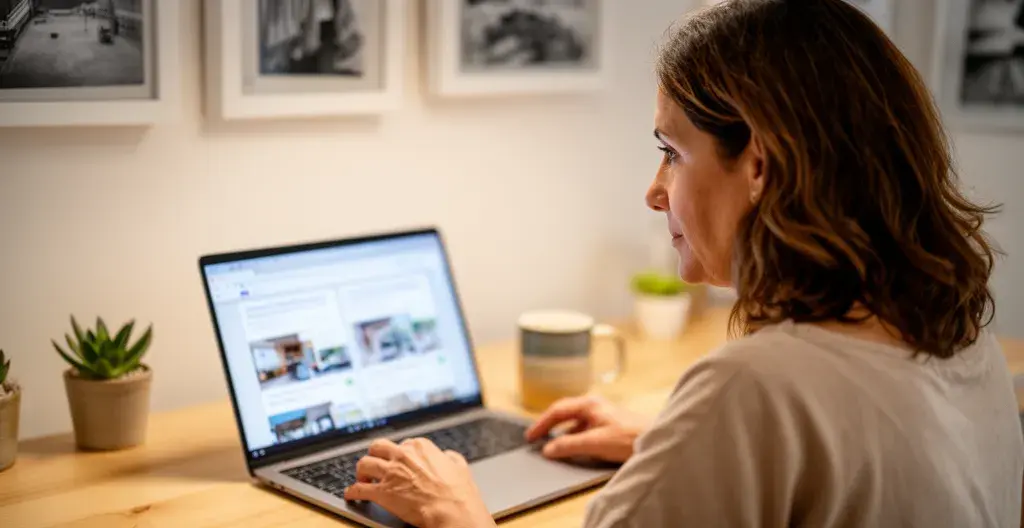 Mujer española consultando información inmobiliaria en portátil desde su hogar en Madrid